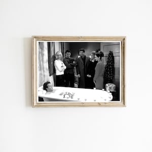 May include: Black and white framed print featuring a scene with six people. One person is in a bathtub, while the others stand around the tub. The print is in a gold-colored frame.