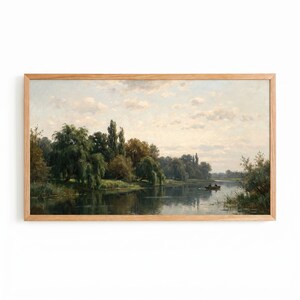 May include: A landscape painting in a light wood frame depicting a calm river flowing past lush green trees and weeping willows under a soft, cloudy sky. A small boat with two figures is visible on the water, reflecting the surrounding scenery.