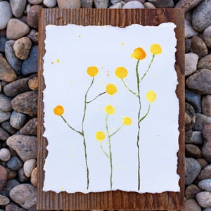 May include: A watercolor painting of yellow flowers on a white background, framed in a rustic wooden frame.