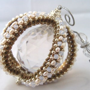 May include: A beaded ornament with a crystal sphere in the center. The ornament is made with brown and white beads and has a silver wire hanger.