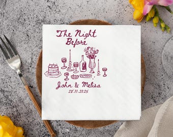 May include: White square napkin with a burgundy illustration of a table setting, including a cake, wine glasses, and a bottle. Text reads "The Night Before" and names "John & Melisa" with a date.