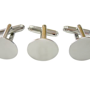 May include: Three silver cufflinks with round, smooth, blank faces. The cufflinks are made of metal and have a polished finish.