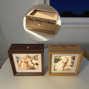 Op de afbeelding: Houten fotolijst met een foto van een stel met een hond. De lijst is bruin en heeft een lade. De tekst "Happy Birthday To Windy" staat op de bovenkant van de lijst.