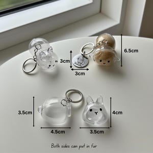 May include: Clear plastic keychains in the shape of animals, including a bunny and a dog, with silver key rings. The keychains are 3 cm to 6.5 cm in height. One keychain has a tag that says "Potato". The text "Both sides can put in fur" is also visible.