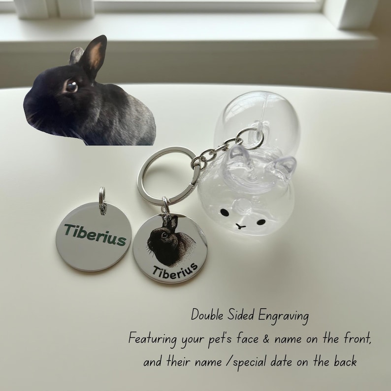 May include: A keychain with a clear bunny-shaped charm and two silver tags. One tag has the name "Tiberius" engraved, and the other features a black and white image of a bunny with the name "Tiberius". The text reads "Double Sided Engraving".