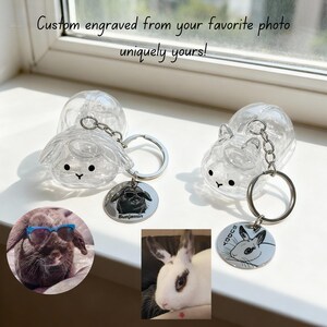 May include: Clear, animal-shaped keychains with engraved pet portraits. Each keychain features a small, round tag with a custom engraved image of a pet. The text "Custom engraved from your favorite photo uniquely yours!" is visible.