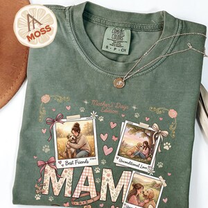 Puede incluir: Camiseta verde Comfort Colors con un gráfico con la palabra "MAM" y tres impresiones fotográficas de una mujer y un perro. La camiseta también tiene el texto "Mother's Days Edition" y "Best Friends". Un collar dorado está drapeado sobre la camiseta.