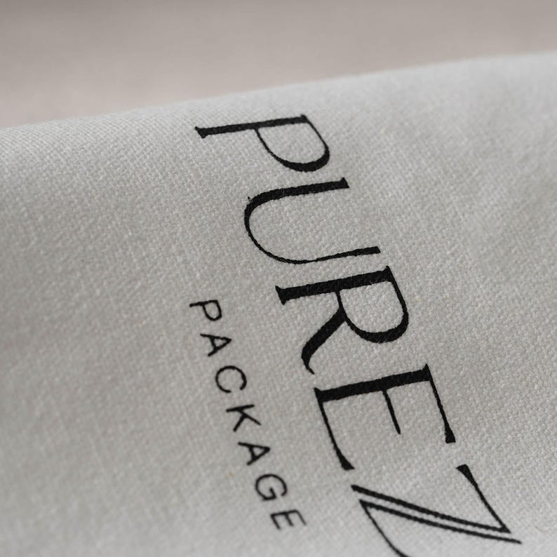 May include: Close-up of a light gray fabric with the words "PUREZ PACKAGE" printed in black. The fabric appears to be folded, with the text slightly curved along the fold.