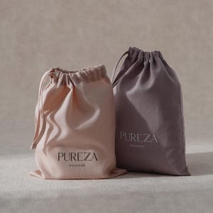 May include: Two drawstring bags in pale pink and muted purple. The bags feature the text "PUREZA PACKAGE" in a minimalist font. The bags are made of a soft, textured fabric, and the drawstring is visible at the top, creating a gathered effect.