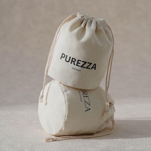 Pode incluir: Dois sacos com cordão em tom de branco sujo feitos de tecido entrelaçado empilhados verticalmente. O saco superior apresenta o texto preto PUREZZA PACKAGE impresso na frente. O saco inferior é parcialmente visível com o mesmo texto preto.