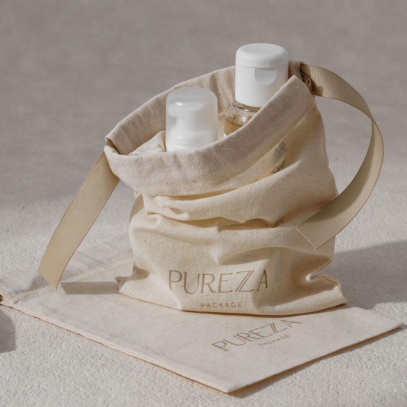 May include: A beige canvas bag with a cream-colored handle and the word "PUREZA PACKAGE" printed on the front. Two white bottles are inside the bag. A matching pouch with the same text is below the bag.