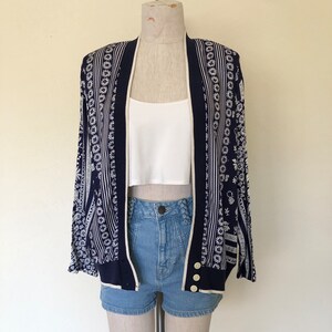 May include: A navy blue cardigan with a white and blue patterned design. The cardigan has a button closure and long sleeves.