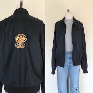 May include: Black bomber jacket with a zipper closure and a patch on the back that reads "U.S. Army Parachute Team Golden Knights".