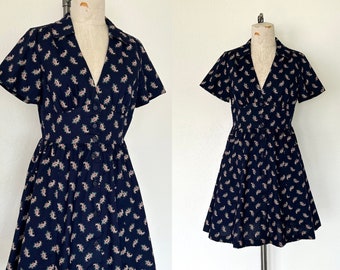 Könnte beinhalten: Ein kurzärmliges, marineblaues Kleid mit Paisley-Muster und Knopfleiste.