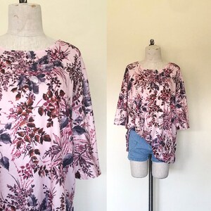 Op de afbeelding: Een roze en paarse blouse met bloemenprint, een losse pasvorm en wijde mouwen. De blouse is gemaakt van een zachte, lichte stof.