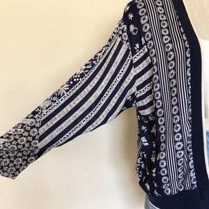 May include: A navy blue and white patterned cardigan with a long sleeve and a ribbed hem.