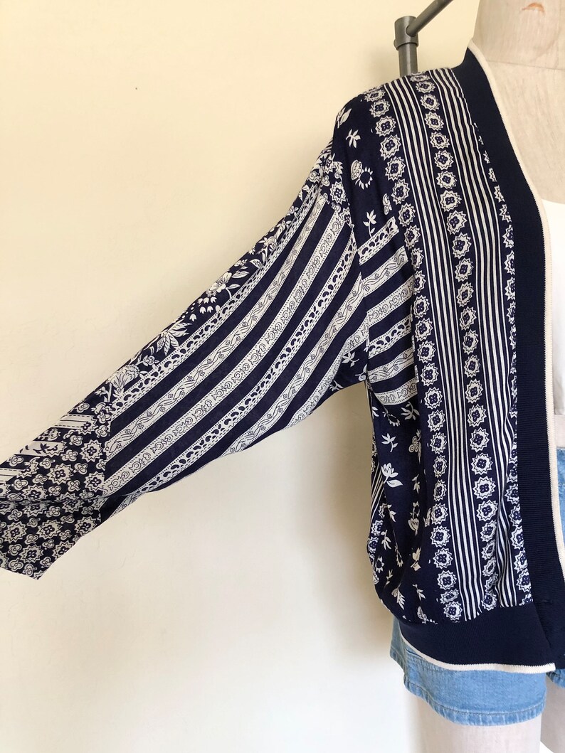 May include: A navy blue and white patterned cardigan with a long sleeve and a ribbed hem.
