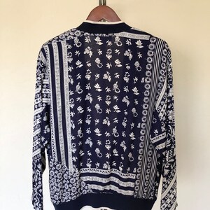 May include: A navy blue long-sleeved cardigan with a white floral pattern. The cardigan is made of a soft, lightweight fabric and has a relaxed fit.