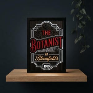 Może przedstawiać: Prostokątny szyld w ramie z tłem o fakturze ciemnego drewna. Napis głosi THE BOTANIST AT Bloomfield's 1910 czerwonymi, białymi i złotymi literami. Projekt zawiera skomplikowane zawijasy oraz białą obwódkę, która jest podświetlona od tyłu.