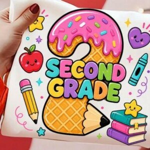 May include: A white fabric surface featuring a colorful graphic design with the text SECOND GRADE. The design includes a large number two shaped like a waffle with pink icing, a red apple, a yellow pencil, a blue crayon, and a stack of books.