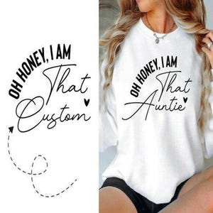 May include: White sweatshirt with the text "OH HONEY, I AM That Auntie" in black script. The sweatshirt is a crew neck style. The image is of a person wearing the sweatshirt.
