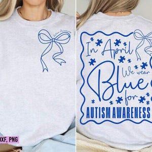 May include: Light gray sweatshirt with blue bow and text. Front features a bow and the words "Autism Awareness". Back has "In April We Wear Blue for Autism Awareness" in a blue puzzle-piece design.
