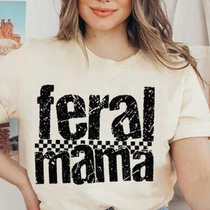 May include: Cream-colored t-shirt with the words "feral mama" in distressed black lettering. The word "mama" is above a black and white checkered pattern. The shirt has rolled-up sleeves.