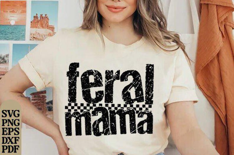 May include: Cream-colored t-shirt with the words "feral mama" in distressed black lettering. The word "mama" is above a black and white checkered pattern. The shirt has rolled-up sleeves.