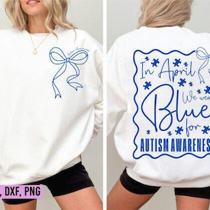 May include: White sweatshirt with blue ribbon and text. The front features a blue ribbon design and the words "Autism Awareness". The back displays "In April We Wear Blue for Autism Awareness" in a blue design with puzzle pieces.