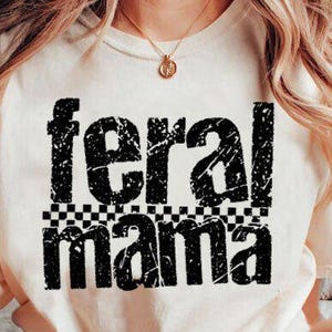 May include: Cream-colored t-shirt with the words "feral mama" in distressed black lettering. The word "feral" is above "mama", separated by a black and white checkered pattern. A gold necklace is visible.