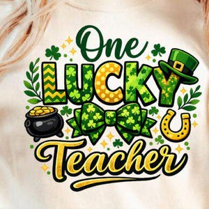 Op de afbeelding: Wit T-shirt met een kleurrijk St. Patrick's Day-ontwerp. Het ontwerp bevat de tekst "One Lucky Teacher" met een klavertje vier, een pot met goud, een hoefijzer en een groene hoed.