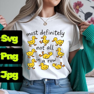 May include: White t-shirt with the phrase "most definitely not all in a row" and cartoon yellow duck illustrations. The shirt is a casual style, suitable for everyday wear.