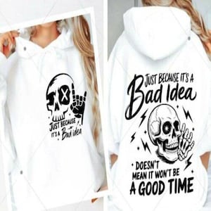 Op de afbeelding: Witte hoodie met een zwarte schedelafbeelding en de tekst "JUST BECAUSE IT'S A Bad idea" op de voorkant. De achterkant heeft een schedel, bliksemschichten en de zin "JUST BECAUSE IT'S A Bad Idea * DOESN'T MEAN IT WON'T BE A GOOD TIME."