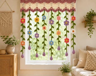 May include: A crochet window valance featuring a scalloped top edge in cream and mauve, with hanging green vines adorned with multi-colored flowers in shades of pink, yellow, blue, purple, and orange, suspended from a wooden curtain rod.