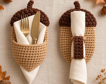 May include: Two crochet acorn-shaped holders in dark brown and tan. One holder functions as a pocket containing a gold-toned fork and knife wrapped in a white napkin. The other holder features a dark brown crochet band securing a white napkin.