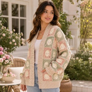 Può includere: Un cardigan a maniche lunghe aperto sul davanti con un motivo a piastrelle all'uncinetto in colori pastello alternati rosa, verde salvia e crema. Ogni quadrato presenta un motivo centrale a teschio. Il capo ha colletto e polsini a coste.