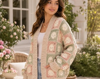 May include: A long-sleeve open-front cardigan featuring a crochet granny square pattern with alternating pastel pink, sage green, and cream colors. Each square displays a central skull motif. The garment has a ribbed cream collar and cuffs.