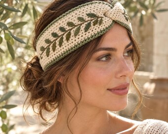 May include: A cream-colored crochet headband featuring a central twisted knot detail and an embroidered olive branch pattern in shades of dark and light green. The headband is finished with a thin green border along the top and bottom edges.