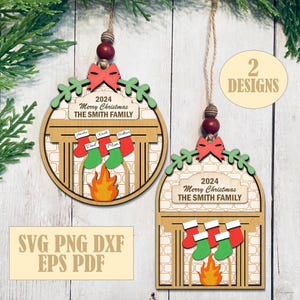 May include: Two wooden Christmas ornaments with a fireplace design. Each ornament has a red bow, green accents, and the text "2024 Merry Christmas THE SMITH FAMILY." One ornament is circular, the other is rectangular. The ornaments have red and green stockings.