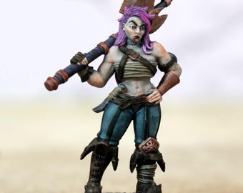 Pode incluir: Figura de fantasia em miniatura de uma mulher guerreira com cabelo roxo, segurando um grande machado. Ela usa calças azuis, botas marrons e uma arnês de couro. A figura é pintada com detalhes e fica em uma base cinza.