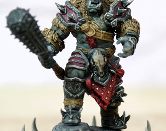 Pode incluir: Figura detalhada de um guerreiro orc de pele verde, segurando uma maça com espinhos. O orc está vestido com uma armadura com detalhes de pele e detalhes vermelhos. A figura está sobre uma base rochosa com espinhos decorativos, mostrando um tema de fantasia.