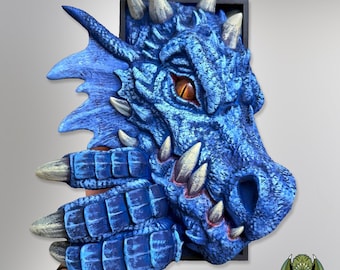 Pode incluir: Escultura de cabeça de dragão azul com uma superfície texturizada detalhada. O dragão tem chifres e garras brancas e afiadas, e um olho laranja. A escultura é montada em uma moldura preta, criando um efeito 3D. As escamas do dragão são de um azul vibrante.