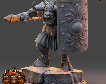 Könnte beinhalten: Graue, detaillierte Miniatur eines Minotaurus-Kriegers, der einen Speer und einen Schild hält. Der Minotaurus hat Hörner, Fell und einen Gürtel mit Löwenmotiv. Der Schild hat ein dekoratives Design. Die Miniatur steht auf einem felsigen Sockel.