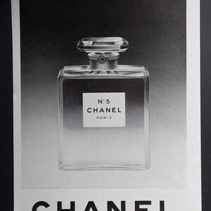 Puede incluir: Anuncio en blanco y negro de perfume Chanel N&deg;5. La imagen muestra un frasco de perfume transparente y rectangular con un tap&oacute;n facetado. La etiqueta dice "N&deg;5 CHANEL PARIS". El logotipo de CHANEL est&aacute; en la parte inferior.