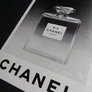 Puede incluir: Impresi&oacute;n en blanco y negro de un frasco de perfume Chanel No. 5. El frasco es rectangular, transparente, con un tap&oacute;n geom&eacute;trico. El logotipo de Chanel es visible.