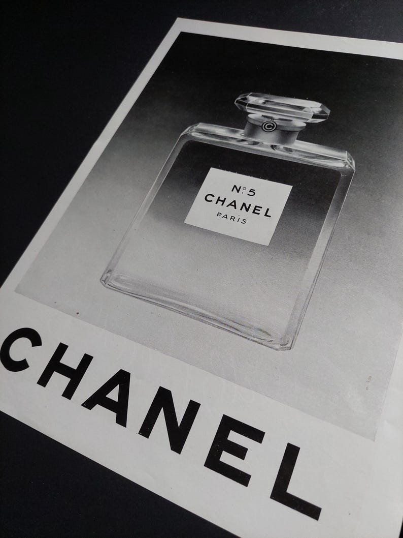 Puede incluir: Impresi&oacute;n en blanco y negro de un frasco de perfume Chanel No. 5. El frasco es rectangular, transparente, con un tap&oacute;n geom&eacute;trico. El logotipo de Chanel es visible.
