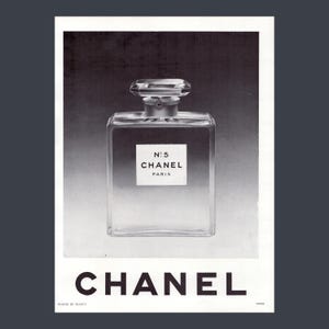 Puede incluir: Anuncio en blanco y negro del perfume Chanel No. 5. El frasco es rectangular con un tap&oacute;n facetado. La etiqueta dice "N&deg;5 CHANEL PARIS". El logotipo de Chanel est&aacute; en la parte inferior.