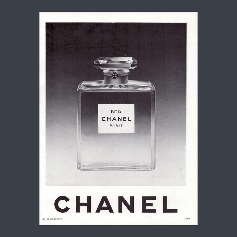 Puede incluir: Anuncio en blanco y negro del perfume Chanel No. 5. El frasco es rectangular con un tap&oacute;n facetado. La etiqueta dice "N&deg;5 CHANEL PARIS". El logotipo de Chanel est&aacute; en la parte inferior.