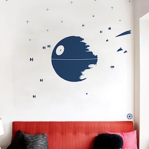 May include: A white wall with a blue and white Death Star decal, surrounded by small white stars. The decal is on a wall in a room with a red sofa and a lamp.