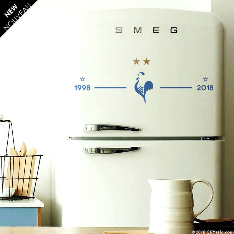 Puede incluir: Un refrigerador blanco con un gallo azul y dos estrellas doradas en la parte delantera. El refrigerador tiene la palabra "SMEG" escrita en la parte superior y los a&ntilde;os "1998" y "2018" en la parte inferior.
